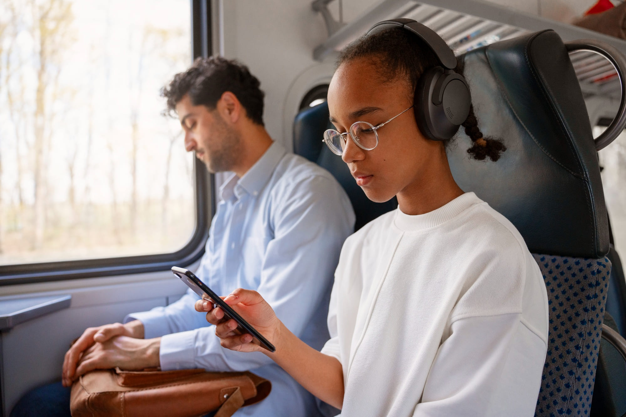 Bambina in treno con le cuffie e il telefono