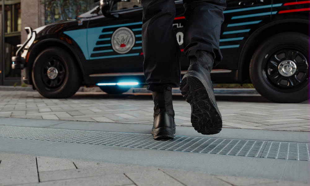 Close-up of tactical boots walking away from a police vehicle parked on a modern urban street
