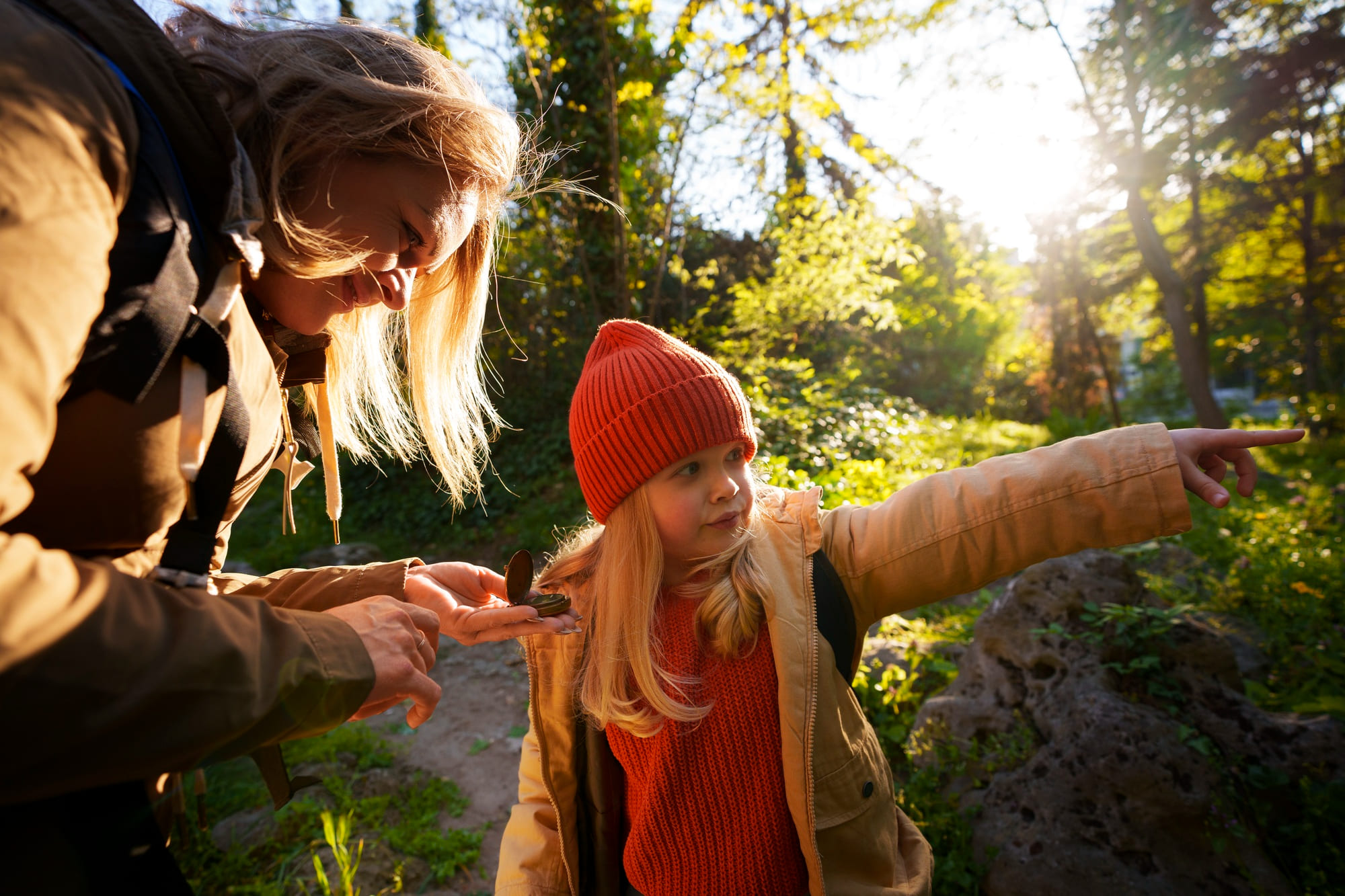 madre con bussola in mano fa trekking nel bosco con la figlia