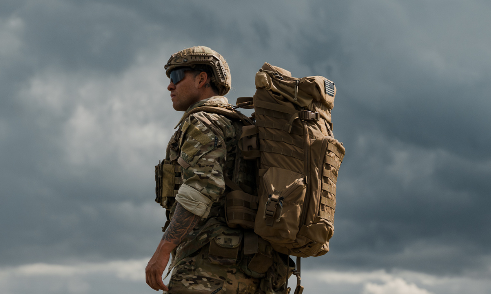Male soldier in tactical gear standing alert under a cloudy sky