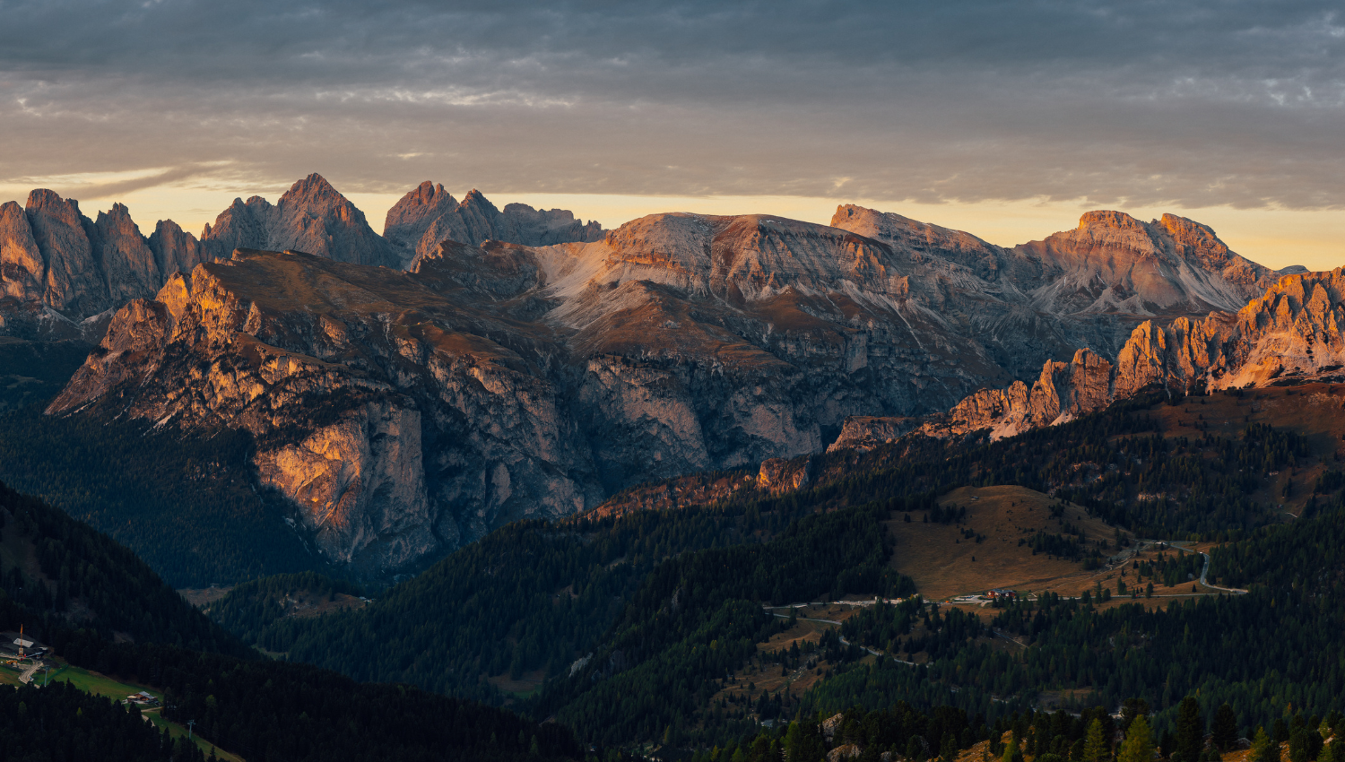 Veduta ampia di una catena montuosa dolomitica, con le ultime luci del giorno che illuminano le creste rocciose.
