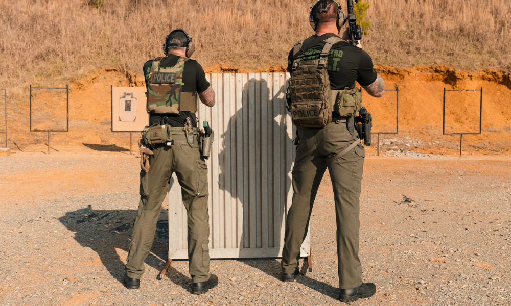 Two law enforcement officers in tactical gear aiming at targets on a shooting range.