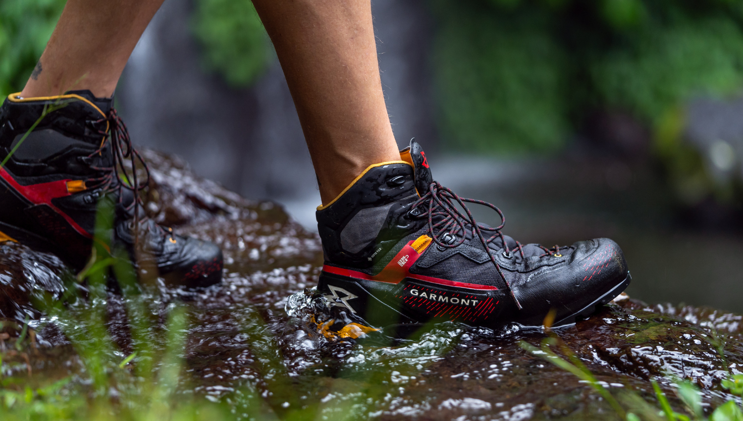 Primo piano di scarponi da trekking Garmont che camminano su un ruscello, dimostrando resistenza all’acqua e grip su superfici bagnate.
