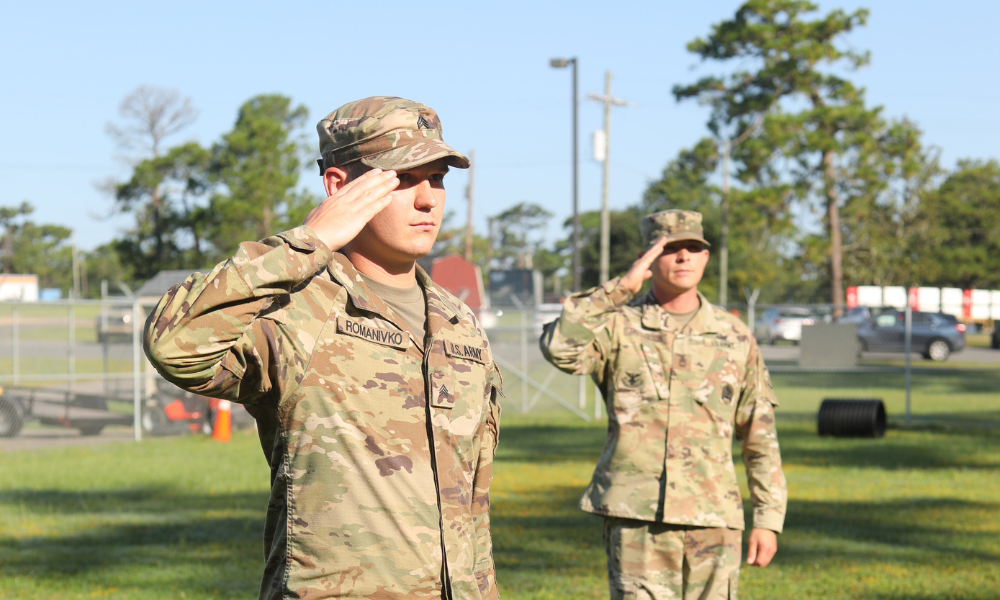 Two U.S. Army soldiers standing outdoors and saluting during a formal moment on base.