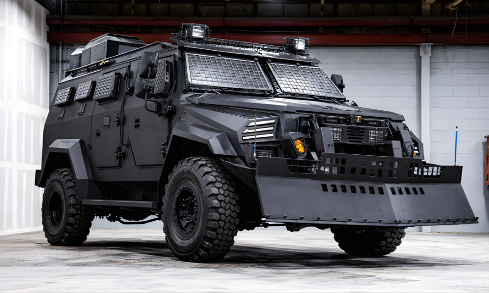 Heavy-duty black armored tactical vehicle with reinforced windows and front ram parked inside a garage.