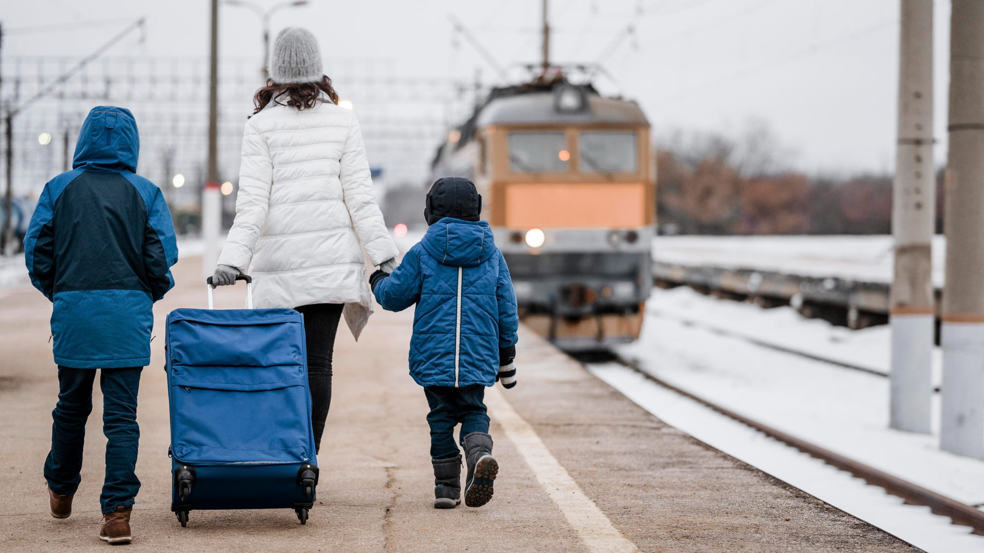 madre e figli con valigia in stazione dei treni
