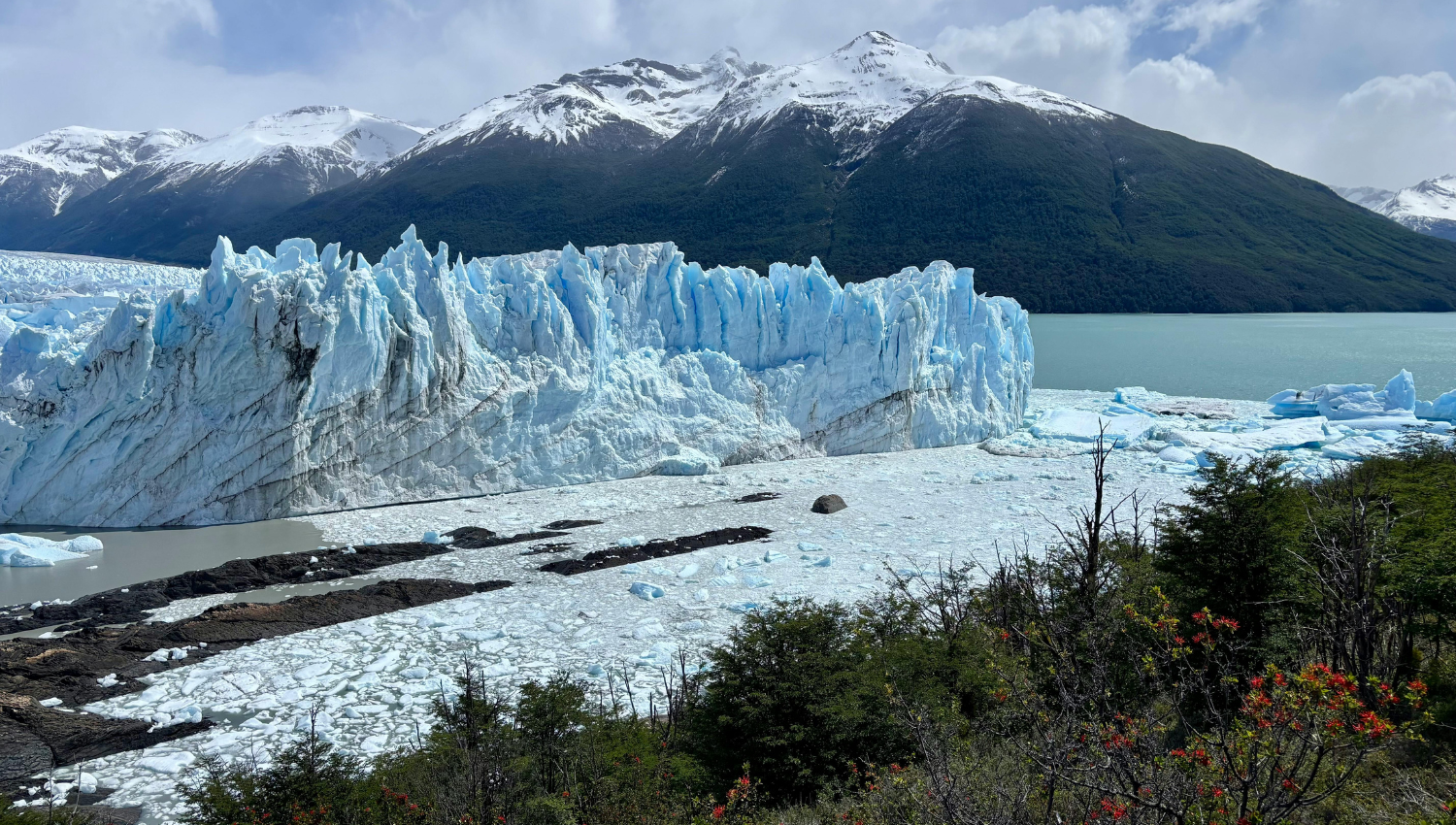 Glaciar Perito Moreno con enormes paredes de hielo frente a un lago, rodeado de montañas nevadas.