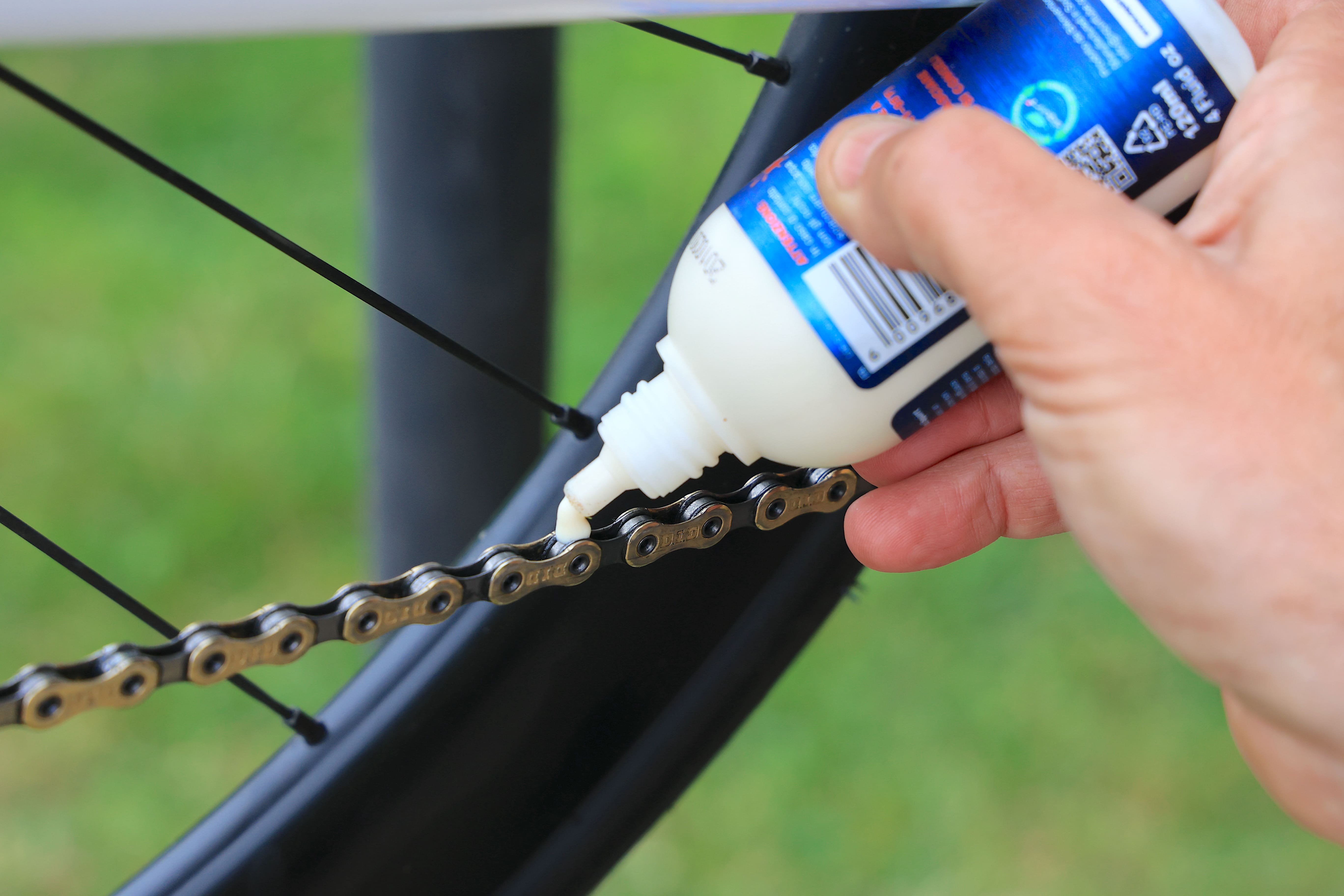mano versa lubrificante su catena bici