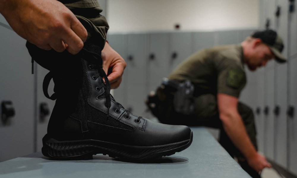     Law enforcement officer lacing up garmont tactical boots in a locker room while another officer prepares gear in the background.