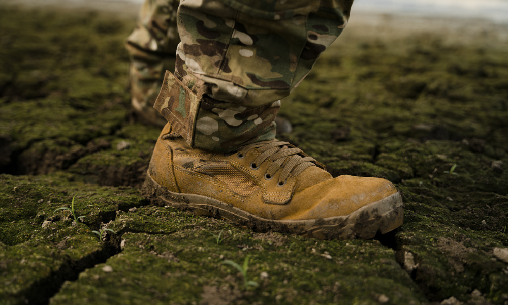     Close-up of a garmont tactical boot stepping on cracked muddy ground during outdoor field operations.