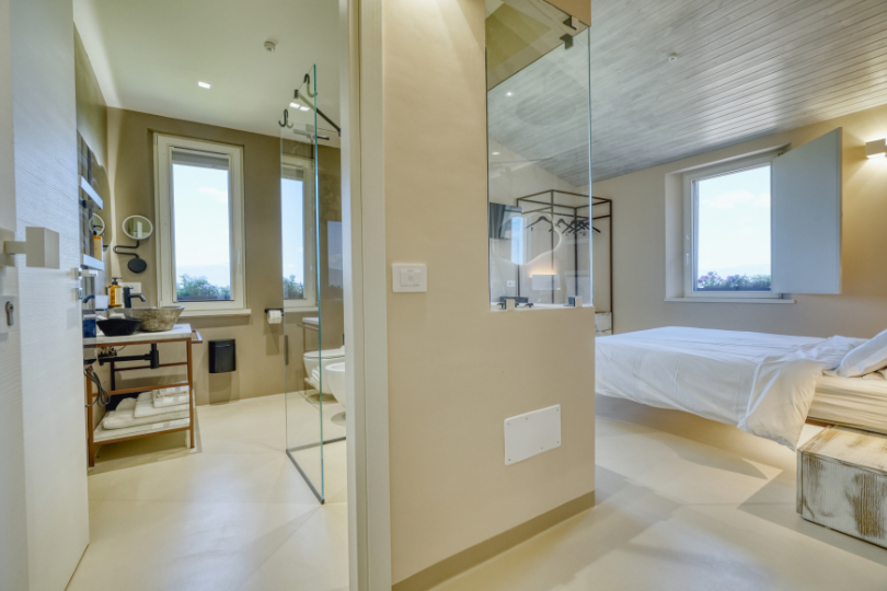 Bagno della camera Moraiolo, con ampia doccia walk-in, prodotti della linea Nuxe, specchi, finestra e vetro trasparente sulla camera.