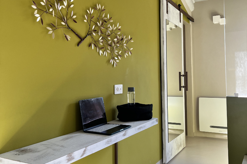 Camera Pendolino, dettaglio della scrivania, pouf e decorazione di ulivo sulla parete e porta scorrevole con ampio specchio.