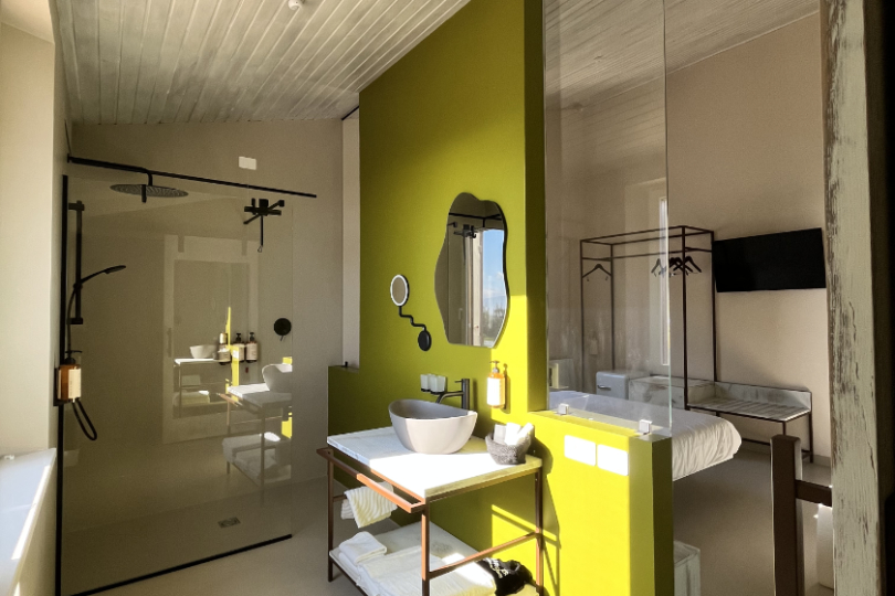 Bagno della camera Pendolino illuminato dalla luce naturale con doccia walk-in, lavabo, asciugamani, prodotti della linea Nuxe e ampi vetri sulla camera.