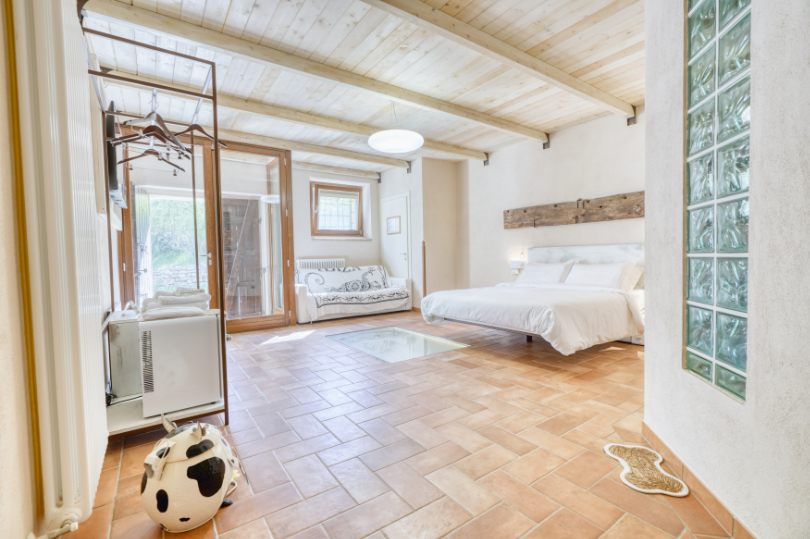 Camera Ascolano, ampia e luminosa, con letto matrimoniale, divano-letto, pavimento in resina, armadio a vista e minibar.
