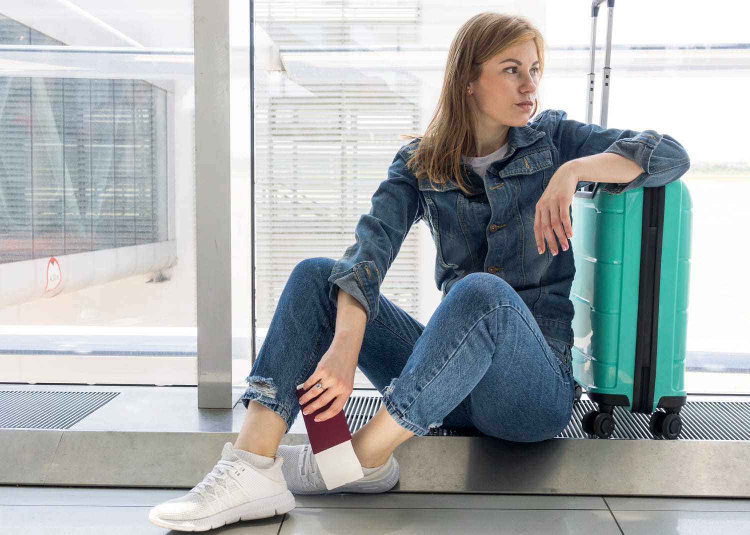donna infastidita in aeroporto con valigia e passaporto