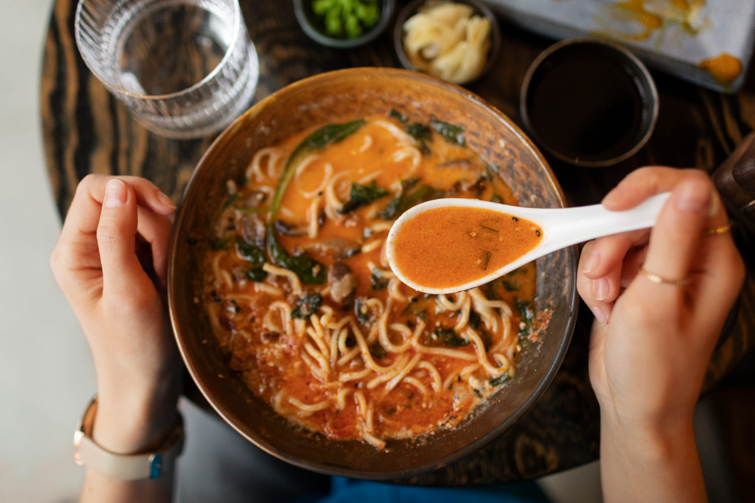 persona con cucchiaio colmo di brodo e ciotola di ramen