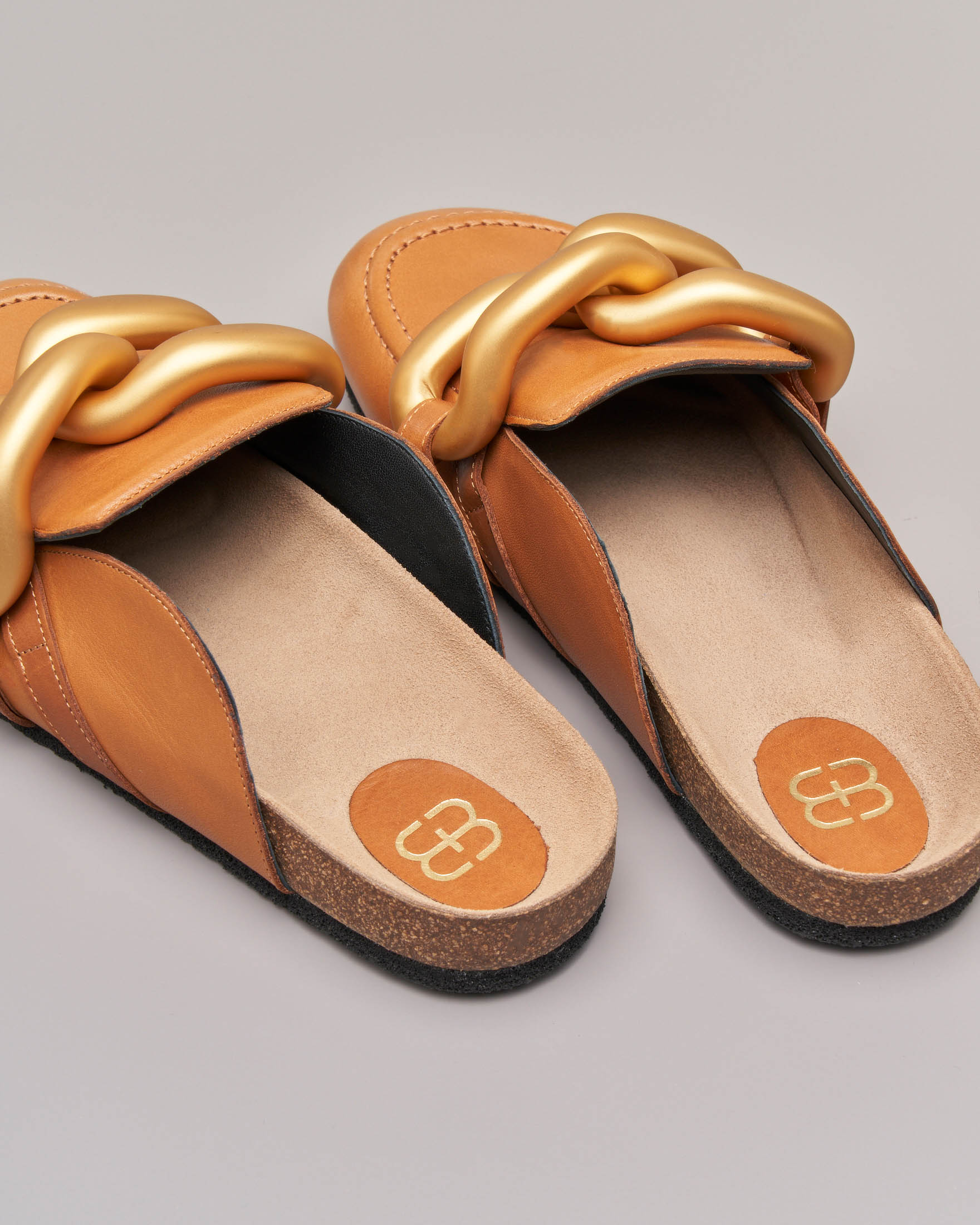 Slippers in pelle color cuoio con punta arrotondata e maxi catena dorata