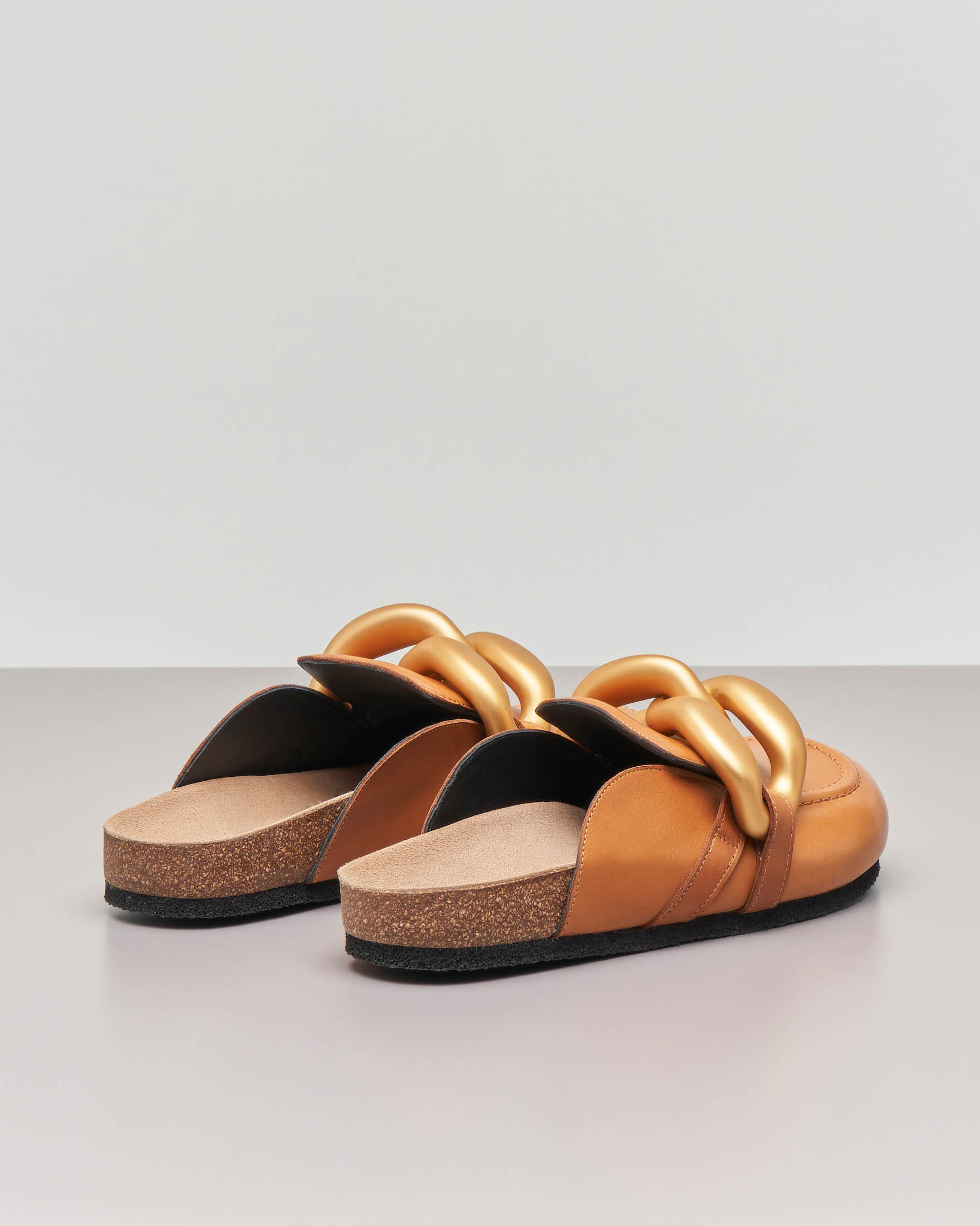 Slippers in pelle color cuoio con punta arrotondata e maxi catena dorata