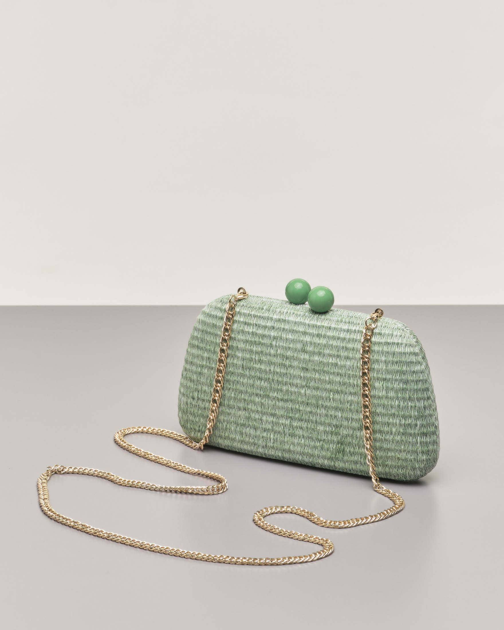 Clutch rigida verde in raffia con chiusura a scatto a sfere tono su tono e  tracolla