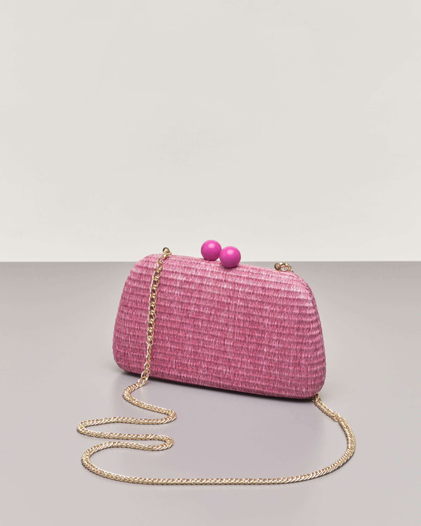 Clutch rigida fucsia in raffia con chiusura a scatto a sfere tono su tono e  tracolla