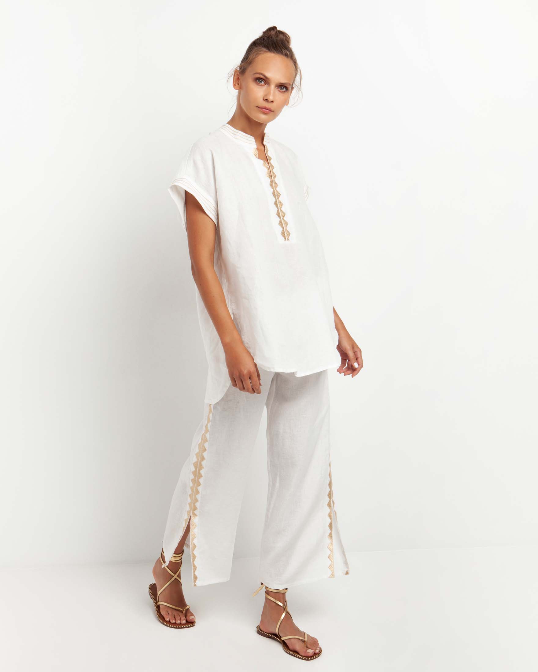 Pantaloni ampi bianchi in lino con spacchetti laterali e ricami oro lungo i fianchi
