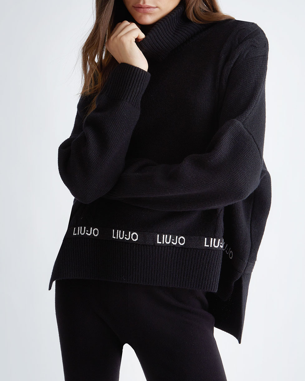 Dolcevita oversize nero in misto lana a trecce con fascia a logo parlato  sul fondo e spacchi laterali