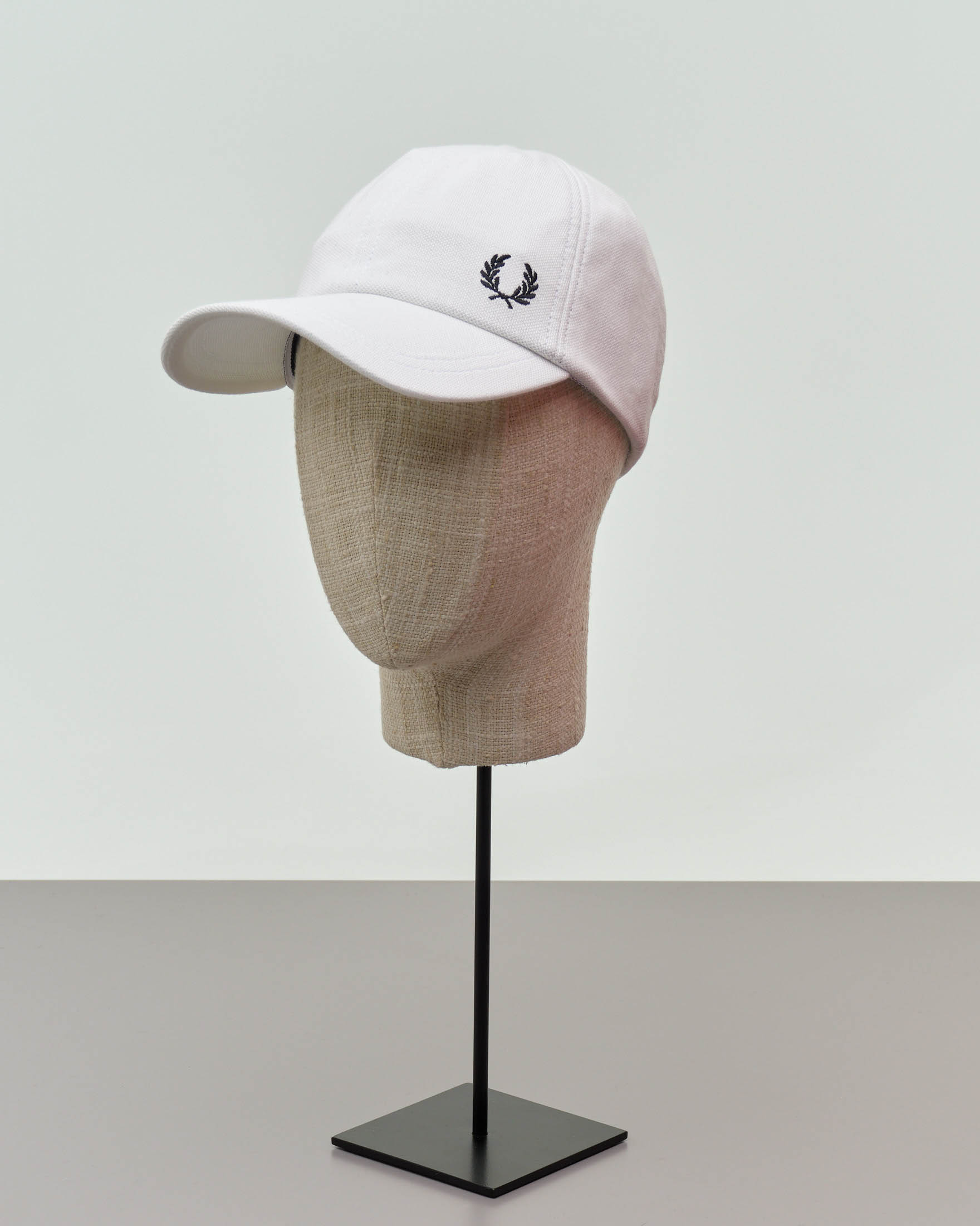Berretto Fred Perry bianco in piquè di cotone con frontino e logo corona d'alloro ricamato
