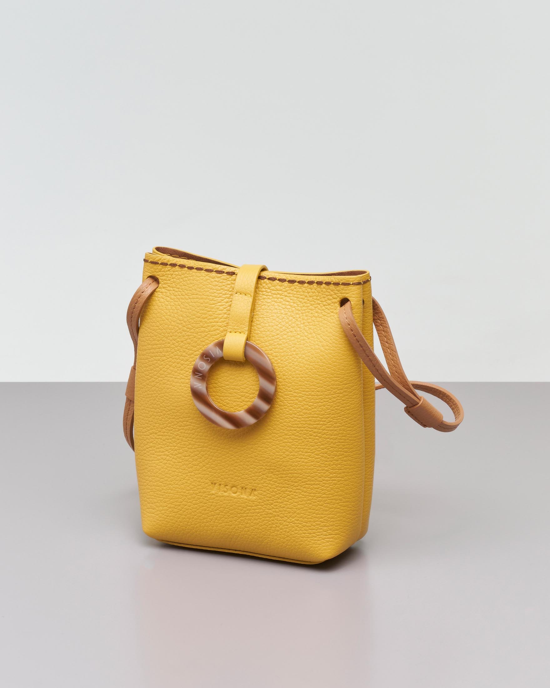 Mini bag in pelle martellata gialla con tracolla color cuoio e chiusura ad anello in osso