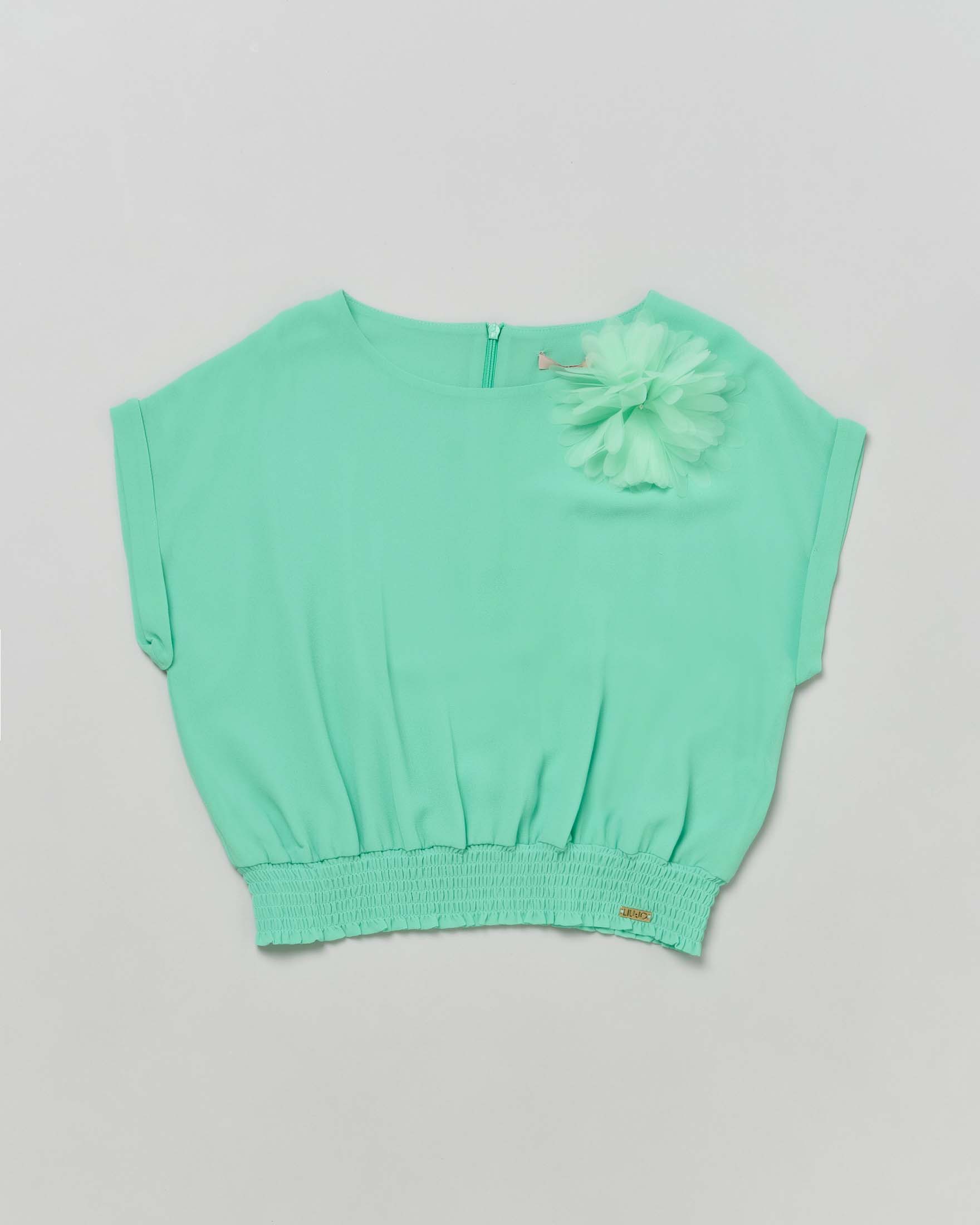 Blusa verde menta in crêpe con punto smock in vita e applicazione floreale