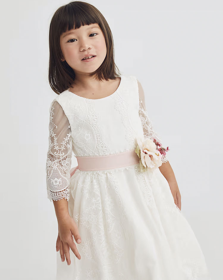 Abito bianco in pizzo con gonna a faldoni e fascia rosa in organza con fiori