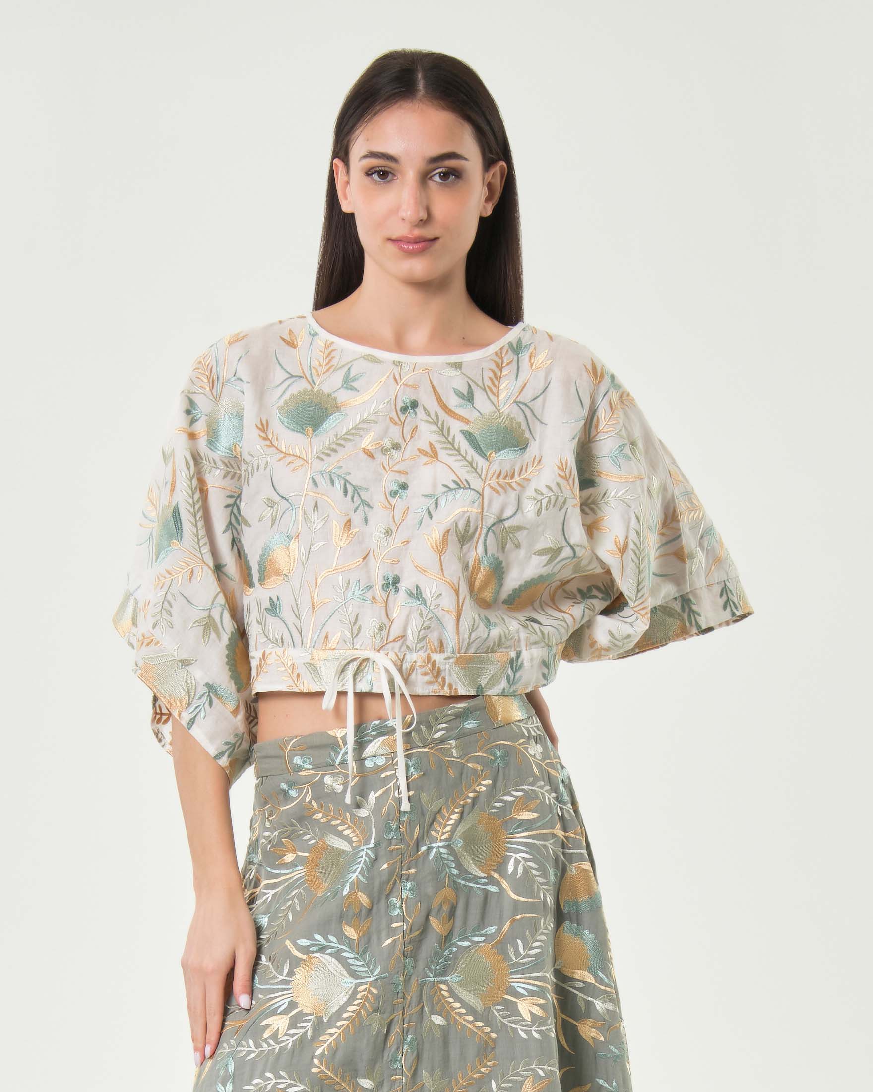 Greek Archaic Kori — Blusa crop Greek Archaic Kori avorio con maniche a tre quarti e ricami floreali oro e ottanio