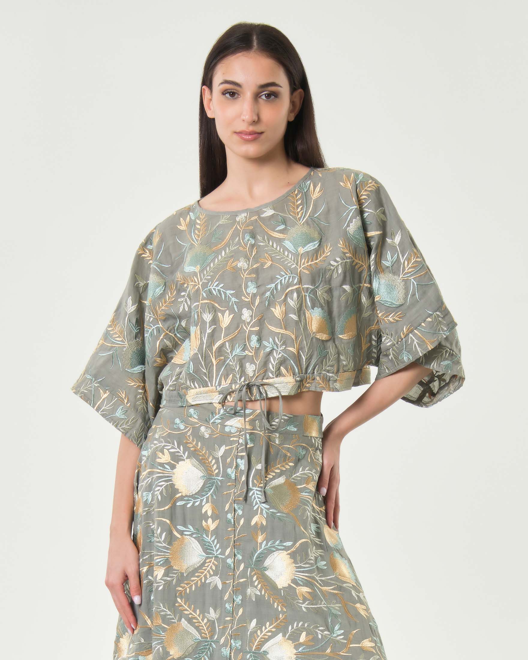 Greek Archaic Kori — Blusa crop Greek Archaic Kori grigia con maniche a tre quarti e ricami floreali oro e ottanio