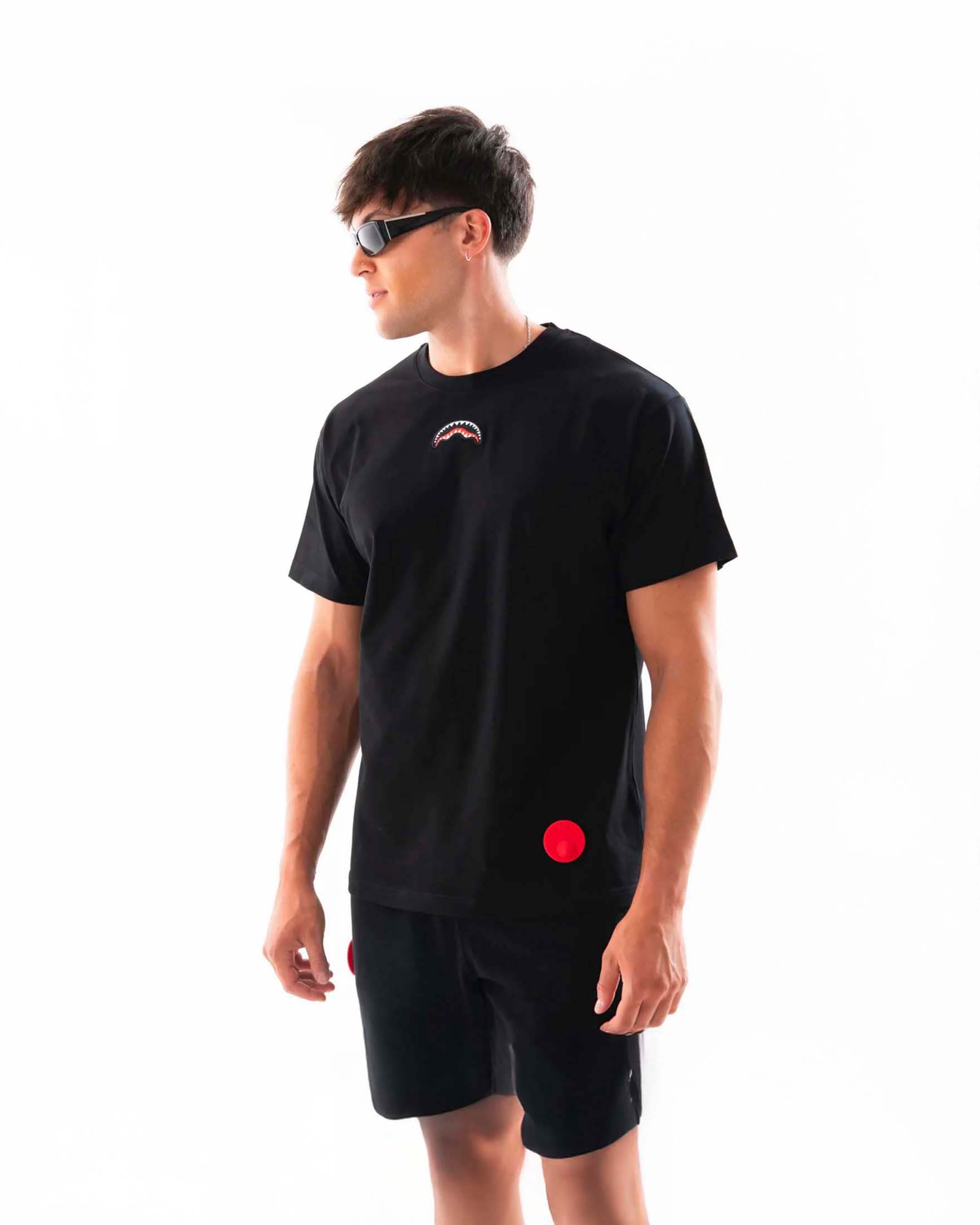 T-shirt nera Sprayground con fauci di squalo ricamate e finto antitaccheggio rosso applicato